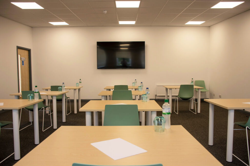 Large training room set up with induvidual desks and a large tv on the wall. 