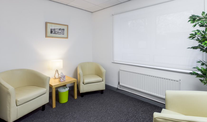 Small  relaxed room with cream coloured "bucket" style arm chairs.  